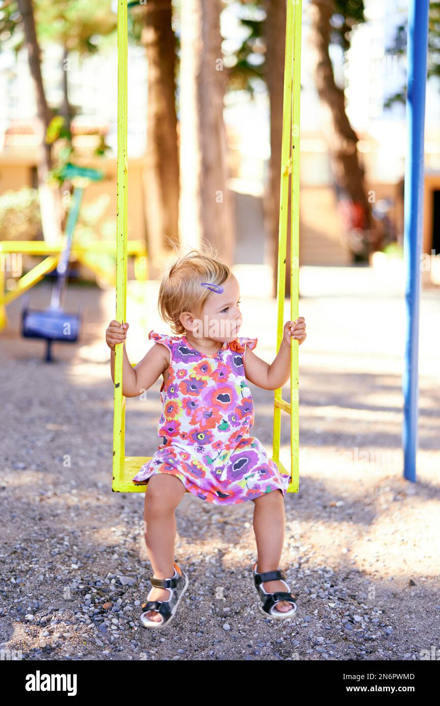 Little girl sitting on a swing in the playground Stock Photo - Alamy
