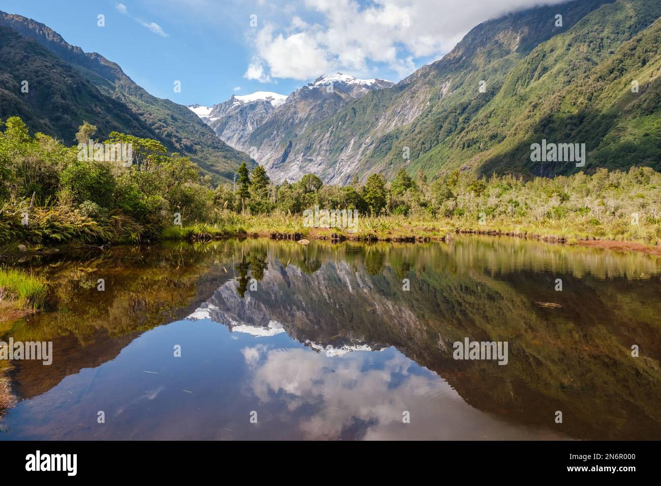 Peters Pool, a mirror lake, reflecting the snow capped mountains at Franz Josef on the South Island of New Zealand Stock Photo