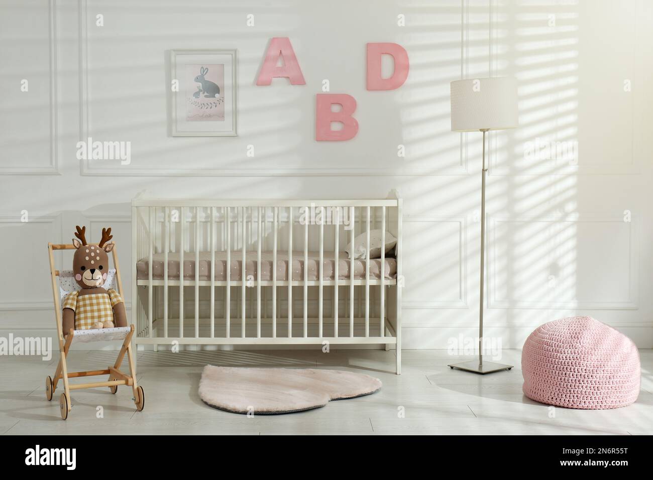 Comfortable crib near wall with pink letters in baby room. Interior ...