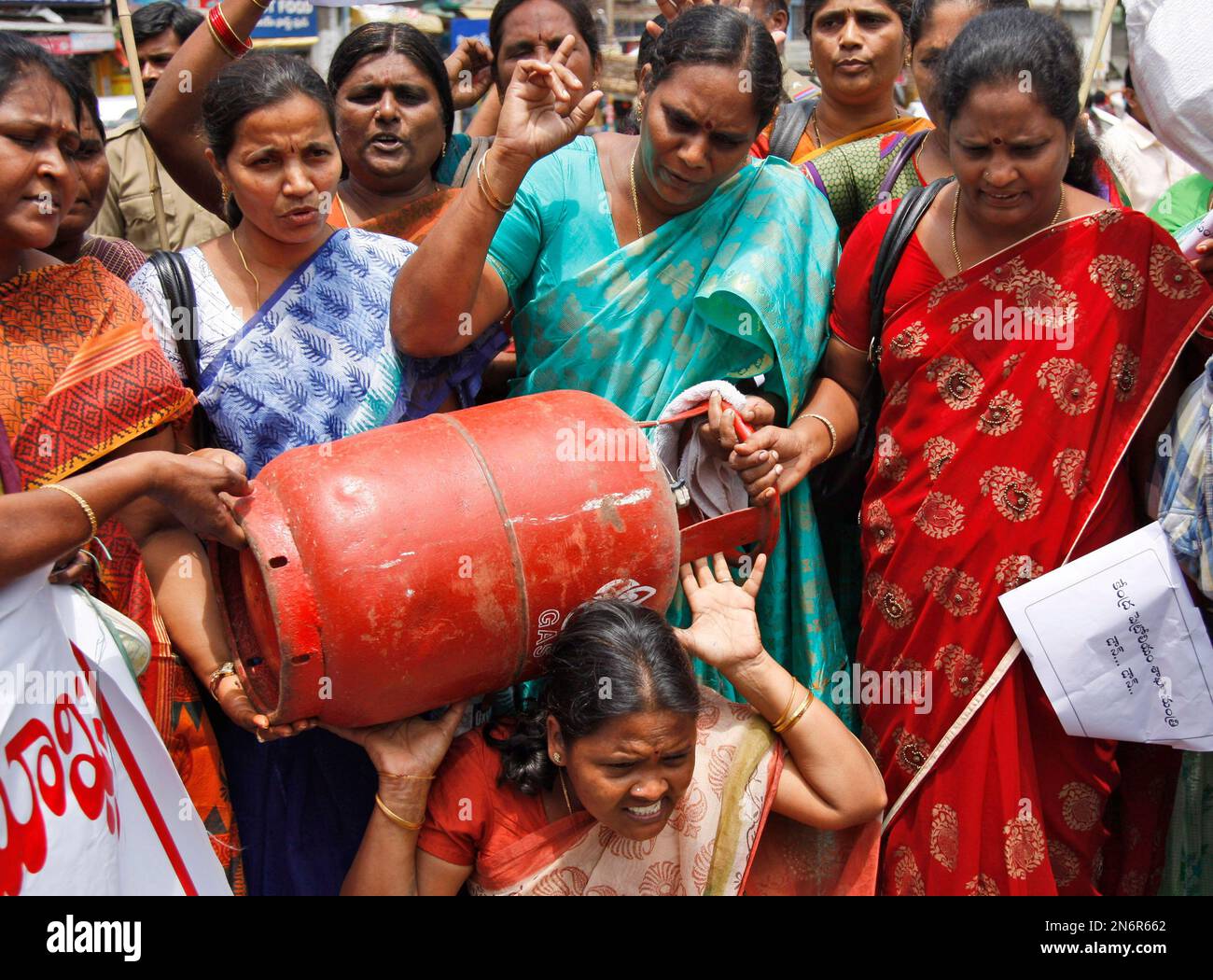 A woman activist carries a liquefied petroleum gas (LPG) cylinder as others shout slogans during a protest in Hyderabad, India, Wednesday, Sept. 4, 2013. LPG prices may be raised by Rupees 50 (