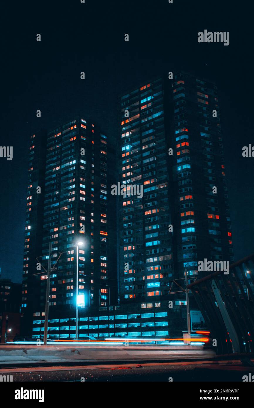 A vertical shot of illuminated modern office building at night with ...