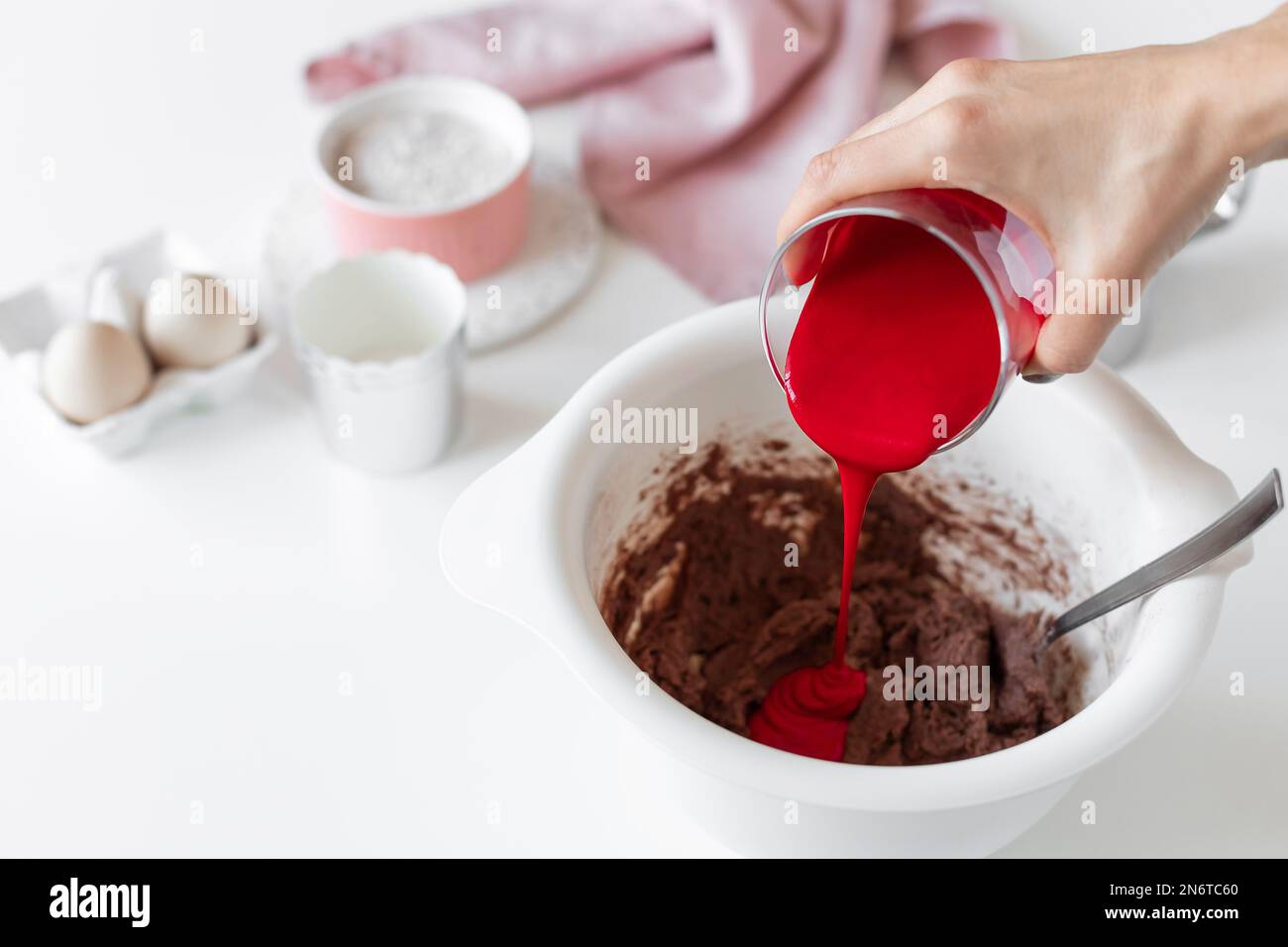 person making red velvet cake and adding red food coloring to batter ...
