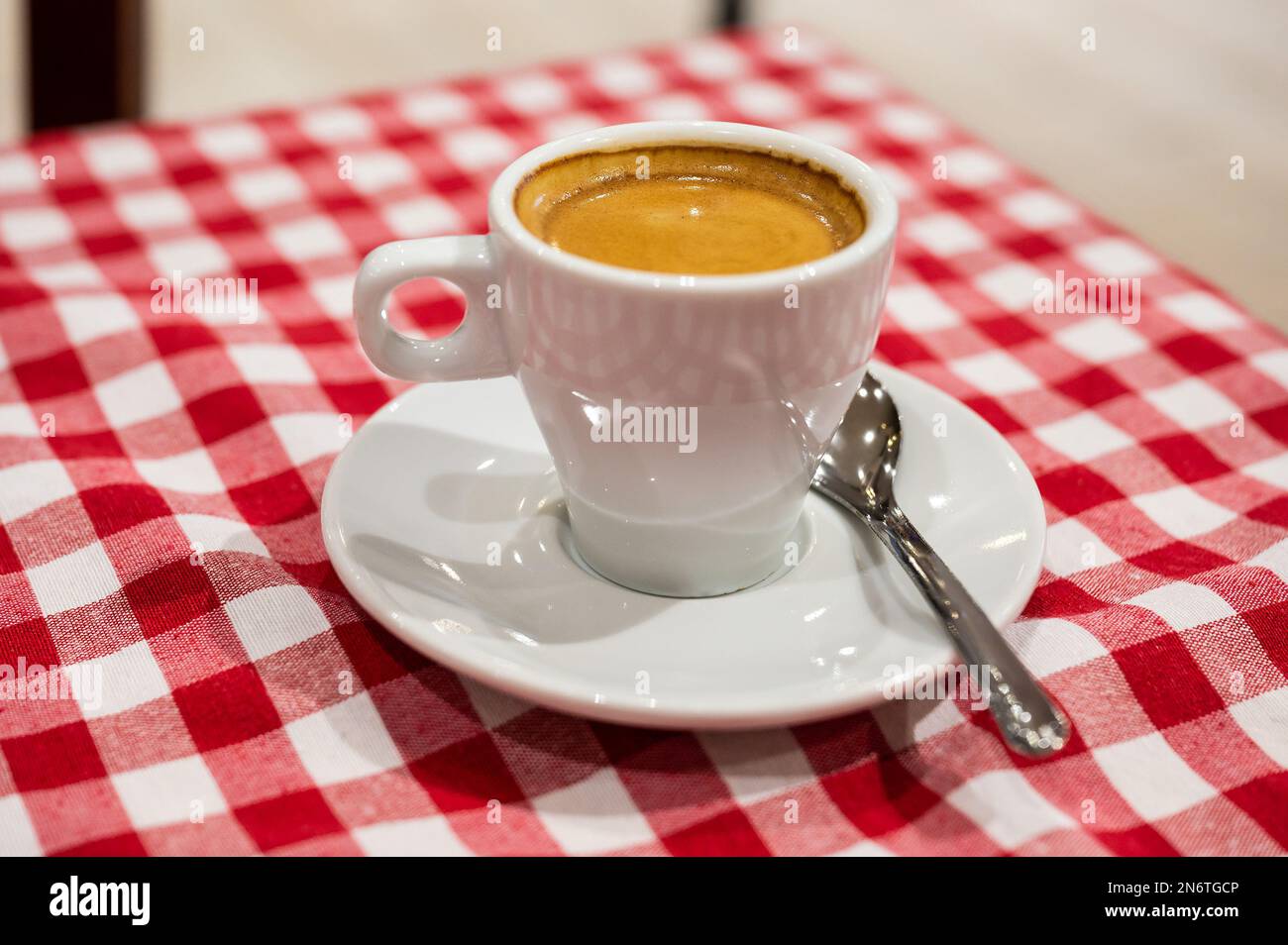 Fresh cup of coffee on a red and white patterned table cloth, Nîmes, France Stock Photo