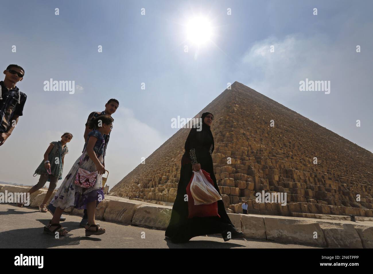 Egyptians walk past Khufu, the largest of pyramids, at the historical