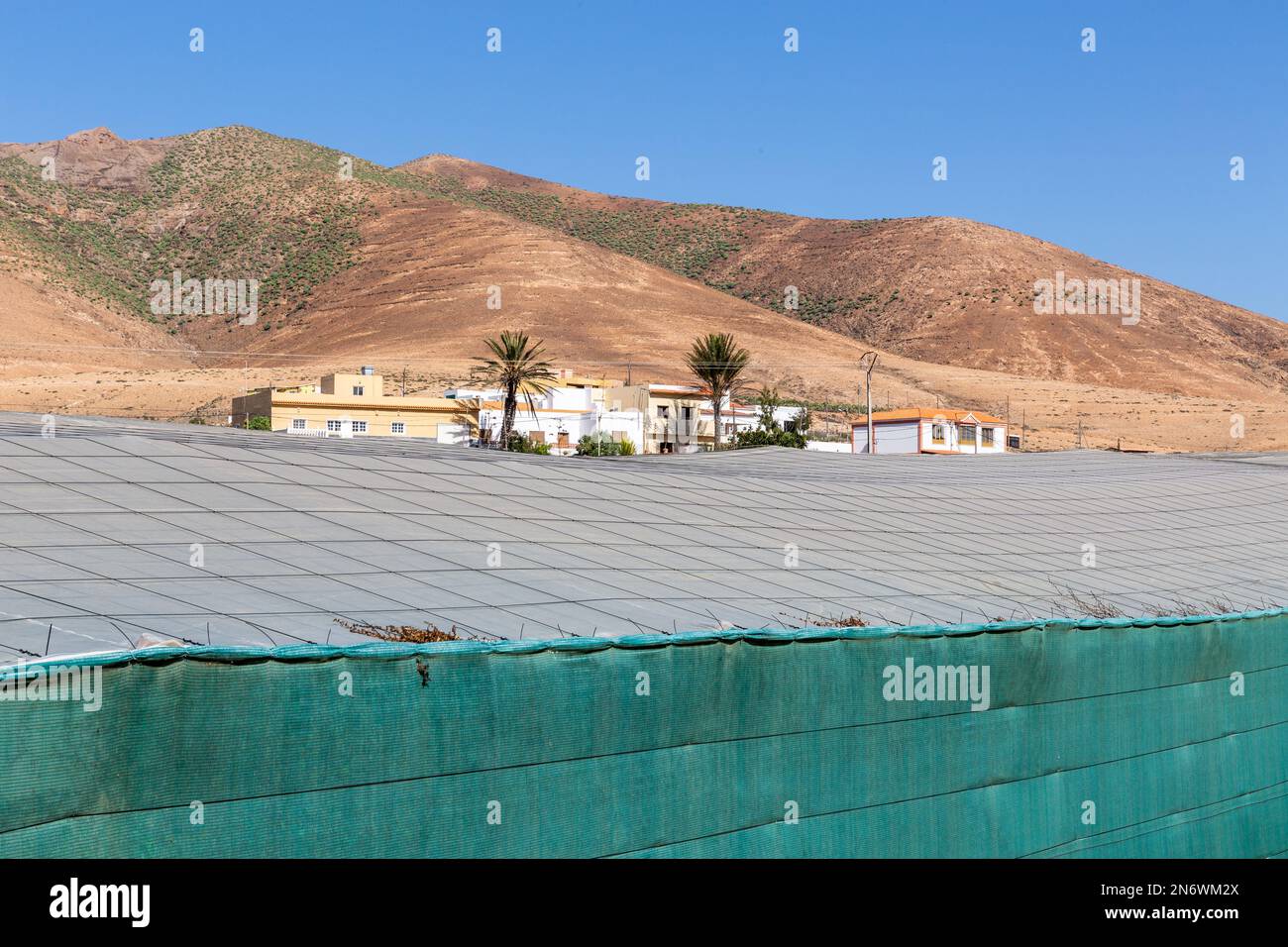 A few dwellings against the backdrop of arid hills. Sunscreen in the foreground. Pajara, Fuerteventura. Stock Photo