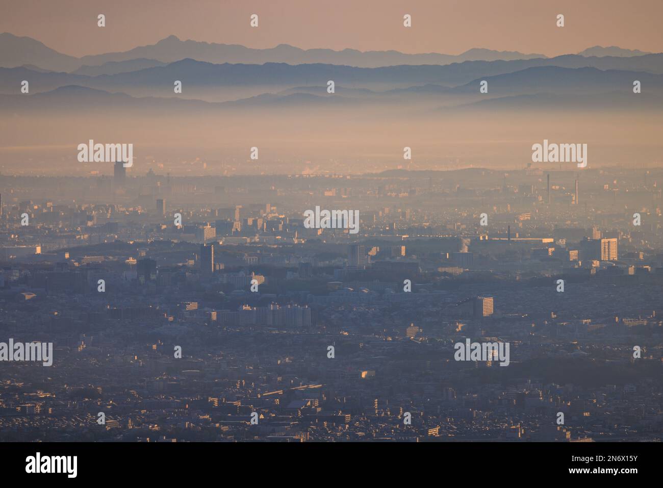 Sprawling city blends with smog layer and distant mountains at sunrise Stock Photo