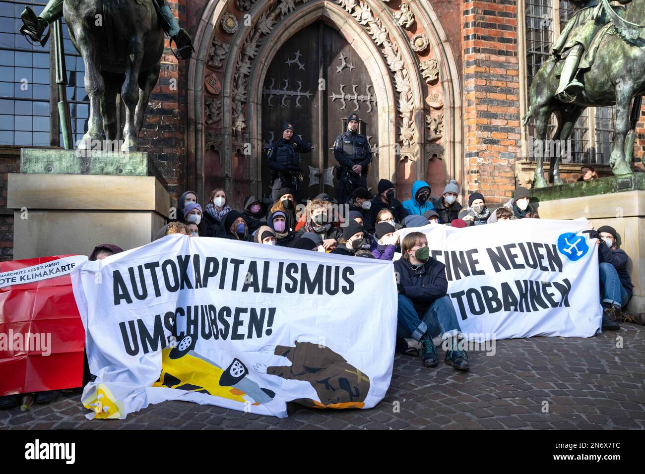 Bremen, Germany. 10th Feb, 2023. Activists demonstrate against transport policy with banners reading 'Overturn car capitalism!' and 'No new freeways' in front of the door of the town hall. The 479th Schaffermahlzeit is held at City Hall with Federal Transport Minister Wissing as guest of honor. Bremen's traditional meal dates back to 1545 and is considered one of the oldest brotherly or friendly meals in the world. Credit: Sina Schuldt/dpa/Alamy Live News Stock Photo