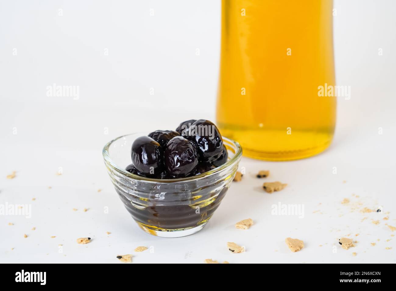 Close up view of glass bottle of olive oil and pickled black olives ...