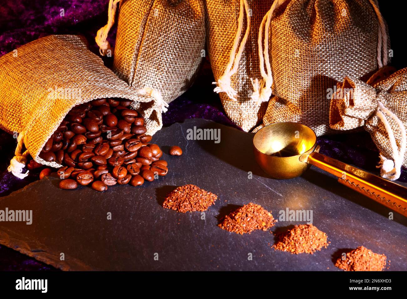 Hessian sacks full of roasted coffee beans with piles of freshly ground coffee Stock Photo
