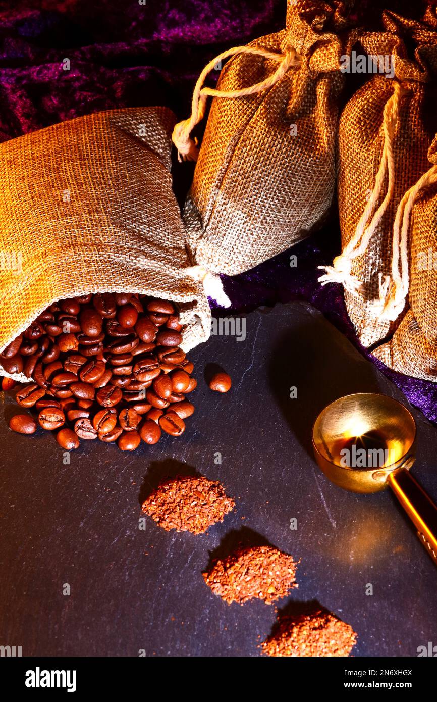 Hessian sacks full of roasted coffee beans with piles of freshly ground coffee Stock Photo