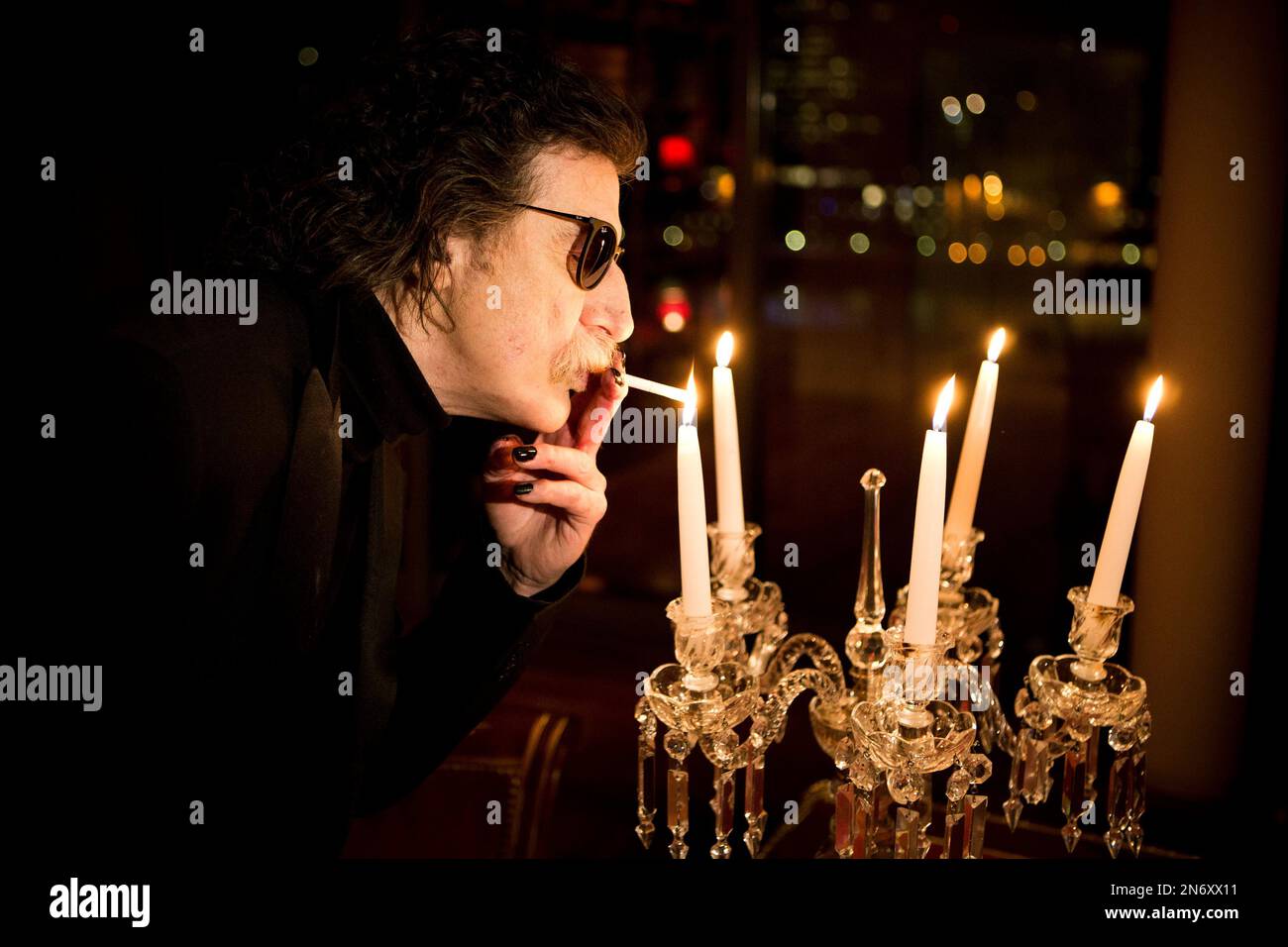 Argentine rock legend Charly Garcia lights a cigarette using a candle flame  before an interview in Buenos Aires, Argentina, Wednesday, Aug. 14, 2013.  Garcia, who is 61 and has a vast career