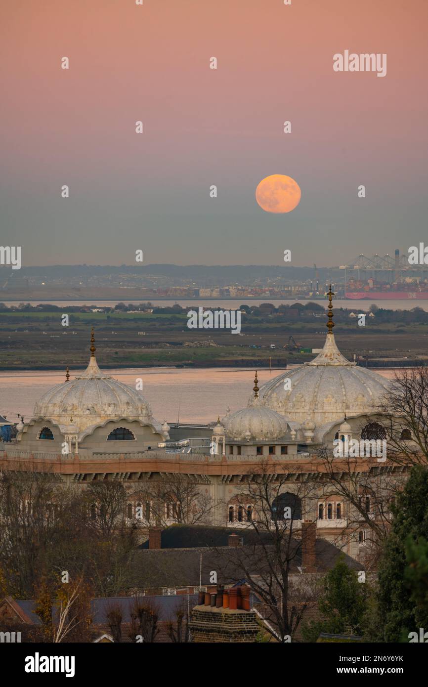 Full moon rising above the DP World London Gateway Port with the Siri Guru Nanak Darbar Gurdwara in Gravesend From windmill hill. Stock Photo