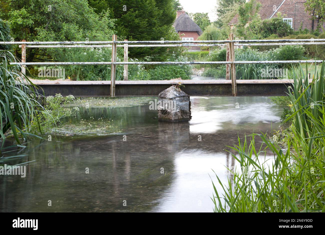A footbridge on the River Ebble in the village of Stratford Tony, near Salisbury in Wiltshire. Stock Photo