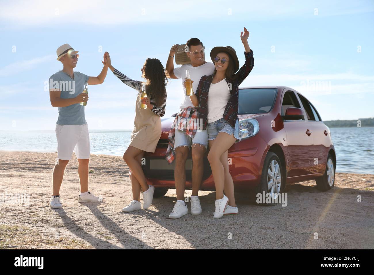 Happy friends having fun near car on beach. Summer trip Stock Photo Alamy