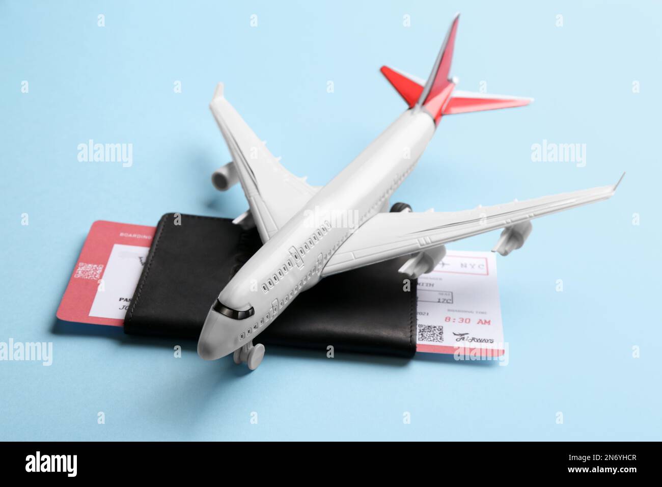 Toy airplane and passport with ticket on light blue background Stock Photo
