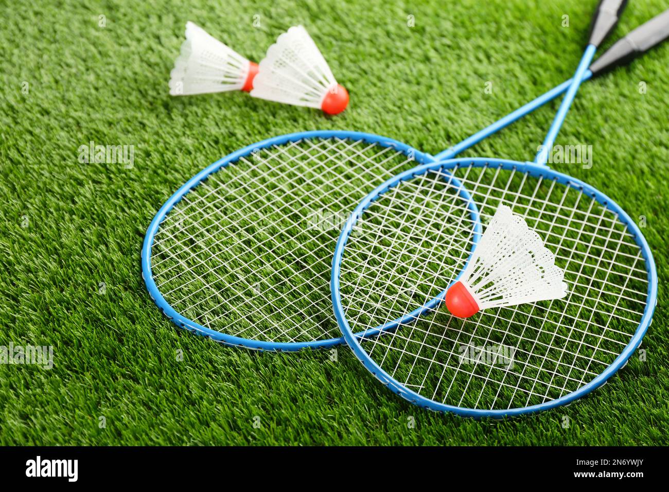 Badminton rackets and shuttlecocks on green grass outdoors Stock Photo