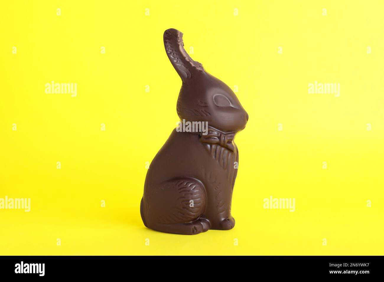 Dark chocolate Easter bunny with bite mark on yellow background Stock