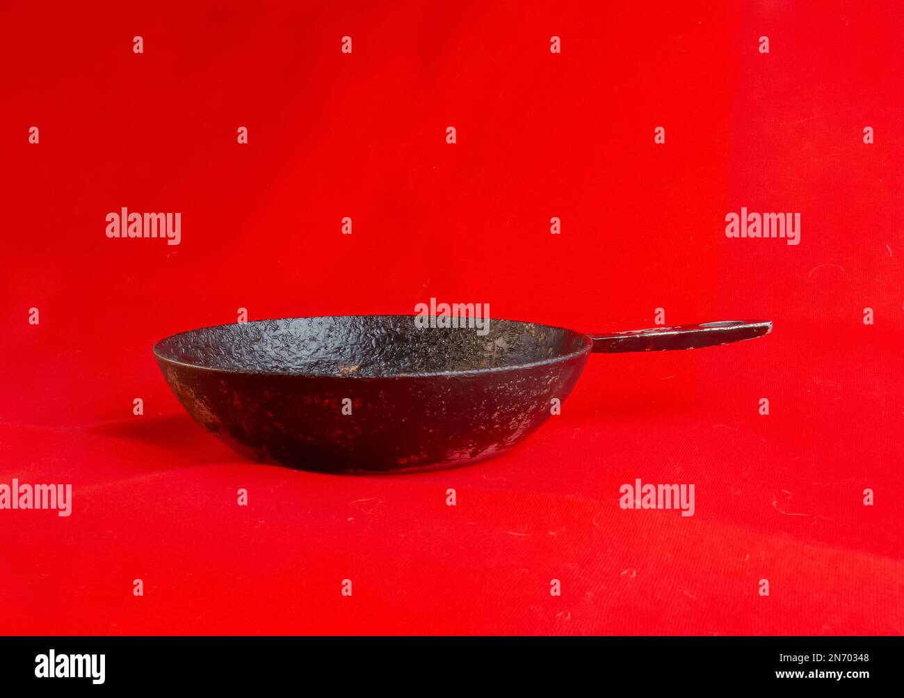 An old cast iron skillet made in circa 1960 against a red background