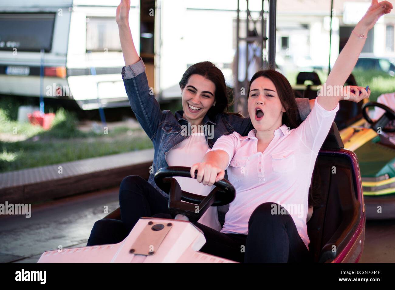 Two young women having a fun bumper car ride at the amusement park