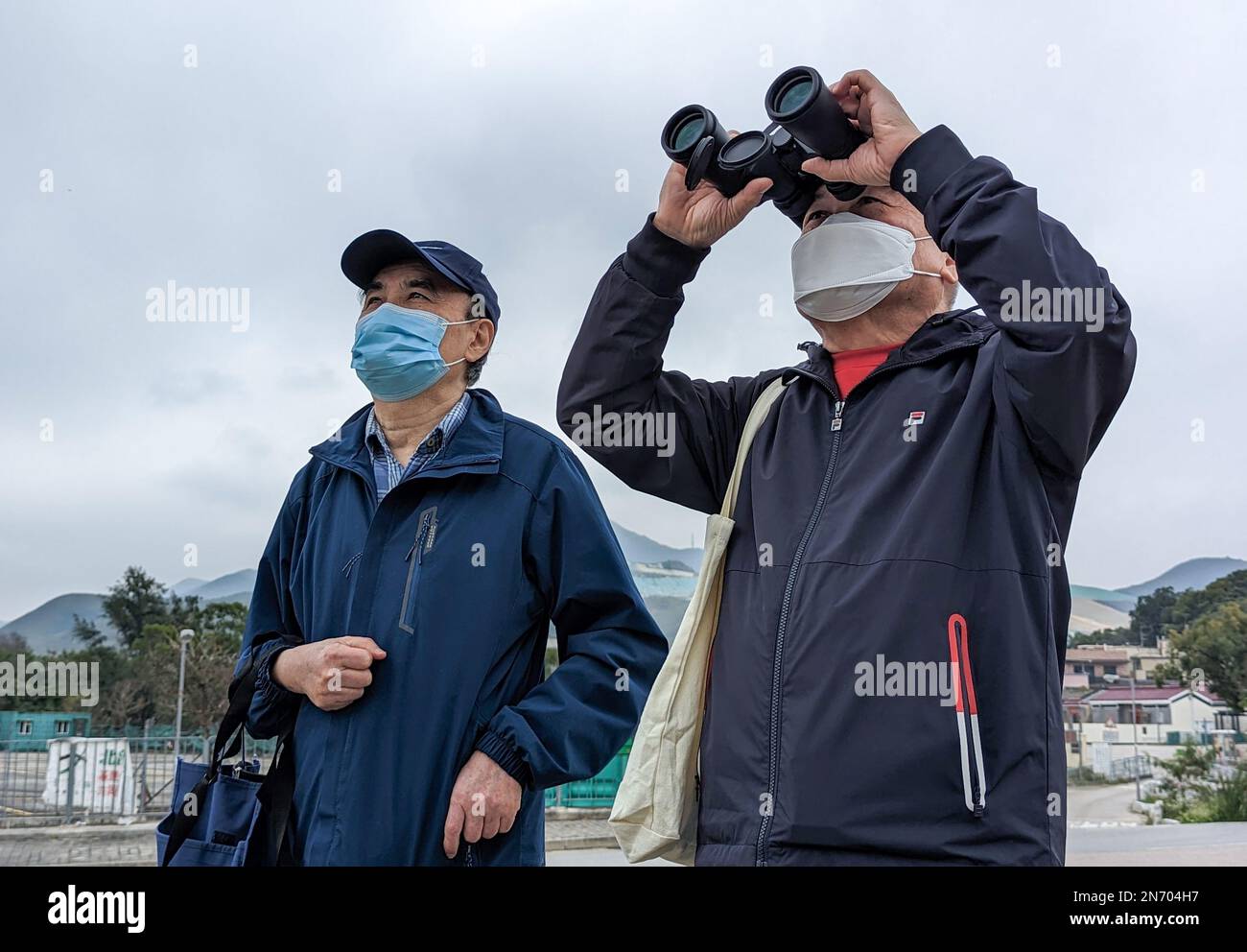 Lim Kian-sang (R), 69, and his friend stepped off a bus outside the new Heung Yuen Wai border crossing facility, they pointed a pair of binoculars north at an apartment building across the Shenzhen border. 05FEB23 SCMP/Kahon Chan Stock Photo