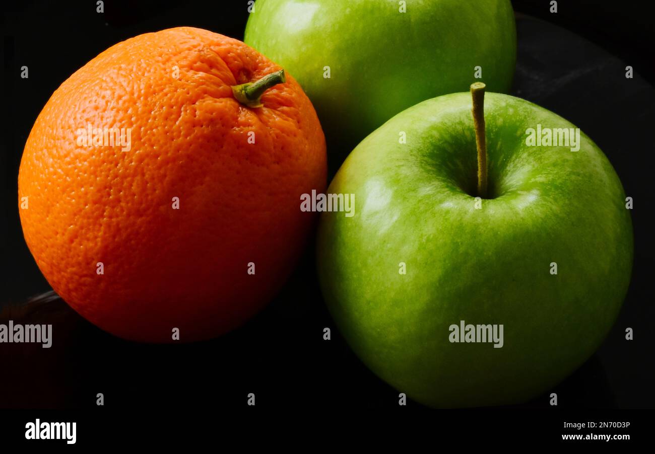 green apples and orange fruit. macro view. isolated fruits on black