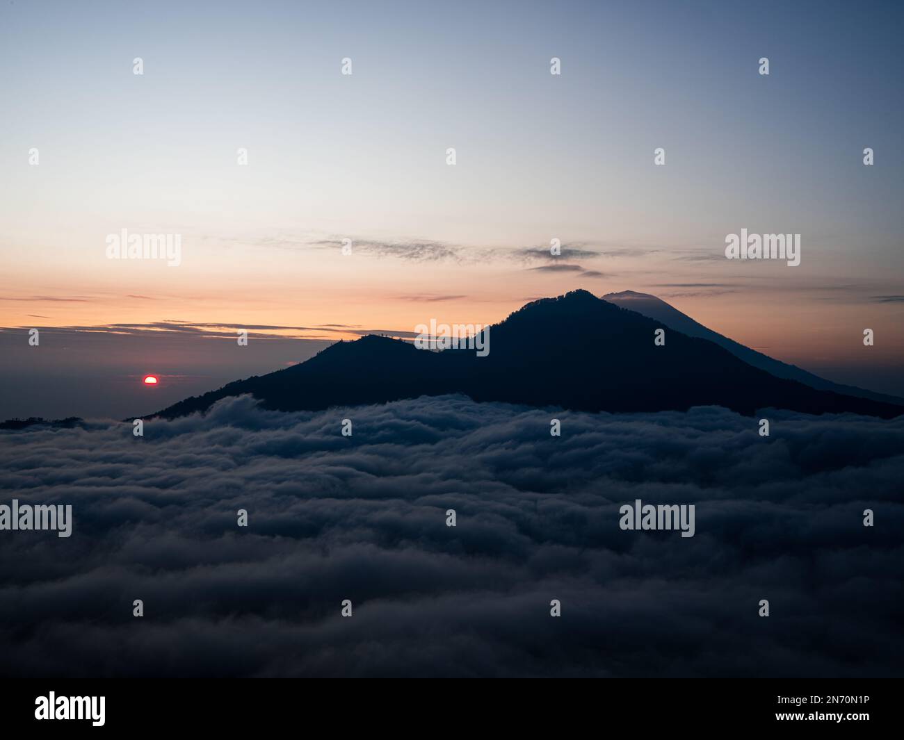 A scenic sunrise above clouds with a mountain volcano view in Bali ...