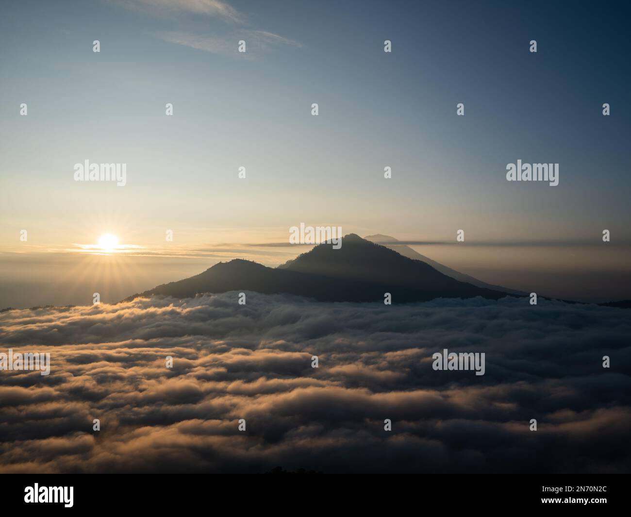 A scenic sunrise above clouds with a mountain volcano view in Bali ...