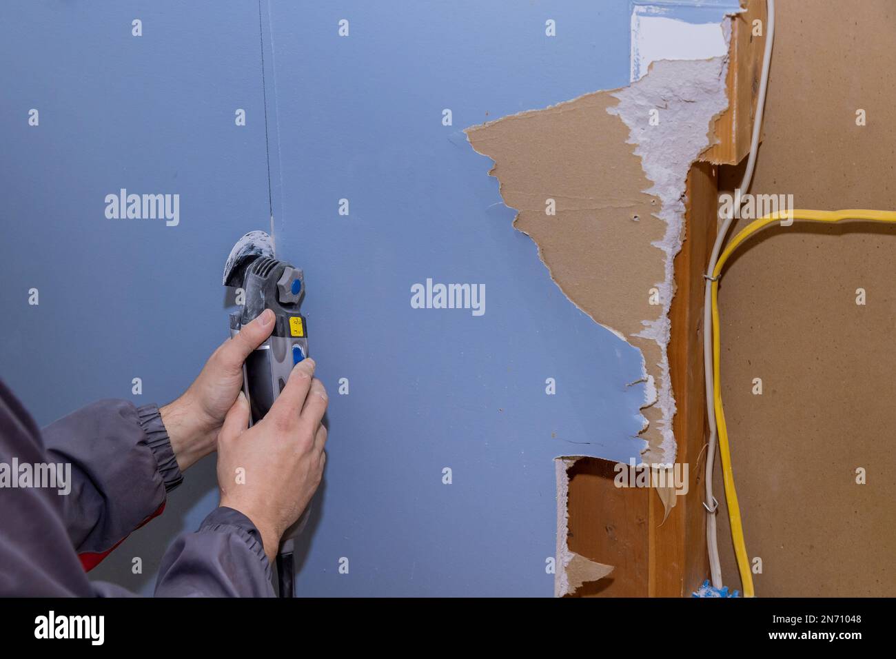 Renovation service work in house cutting off damaged plasterboard with