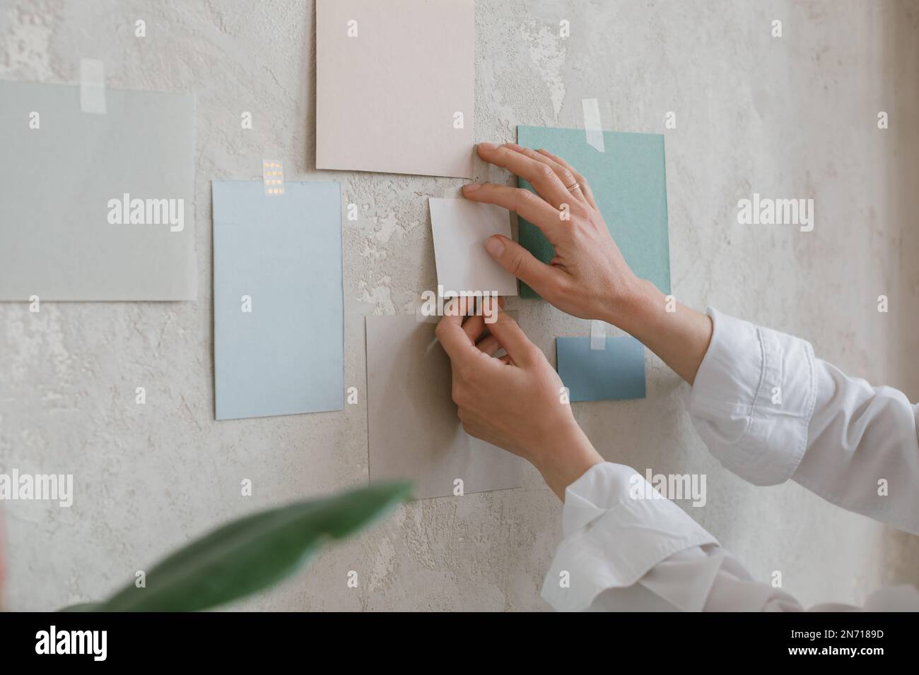 Close-up of a woman taping colour paper samples to a wall Stock Photo