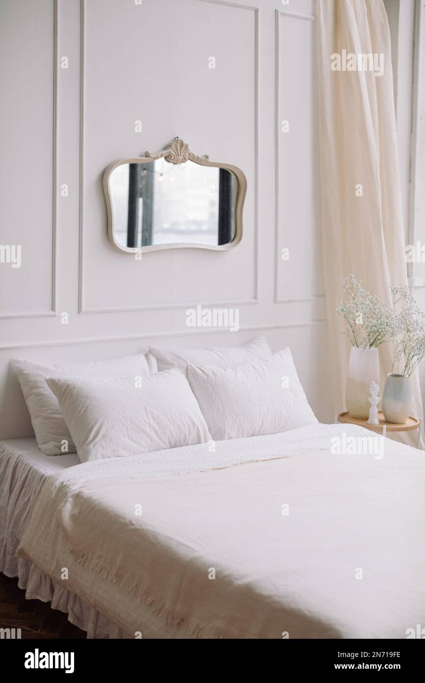 Mirror hanging on a wall over a bed in a bedroom Stock Photo