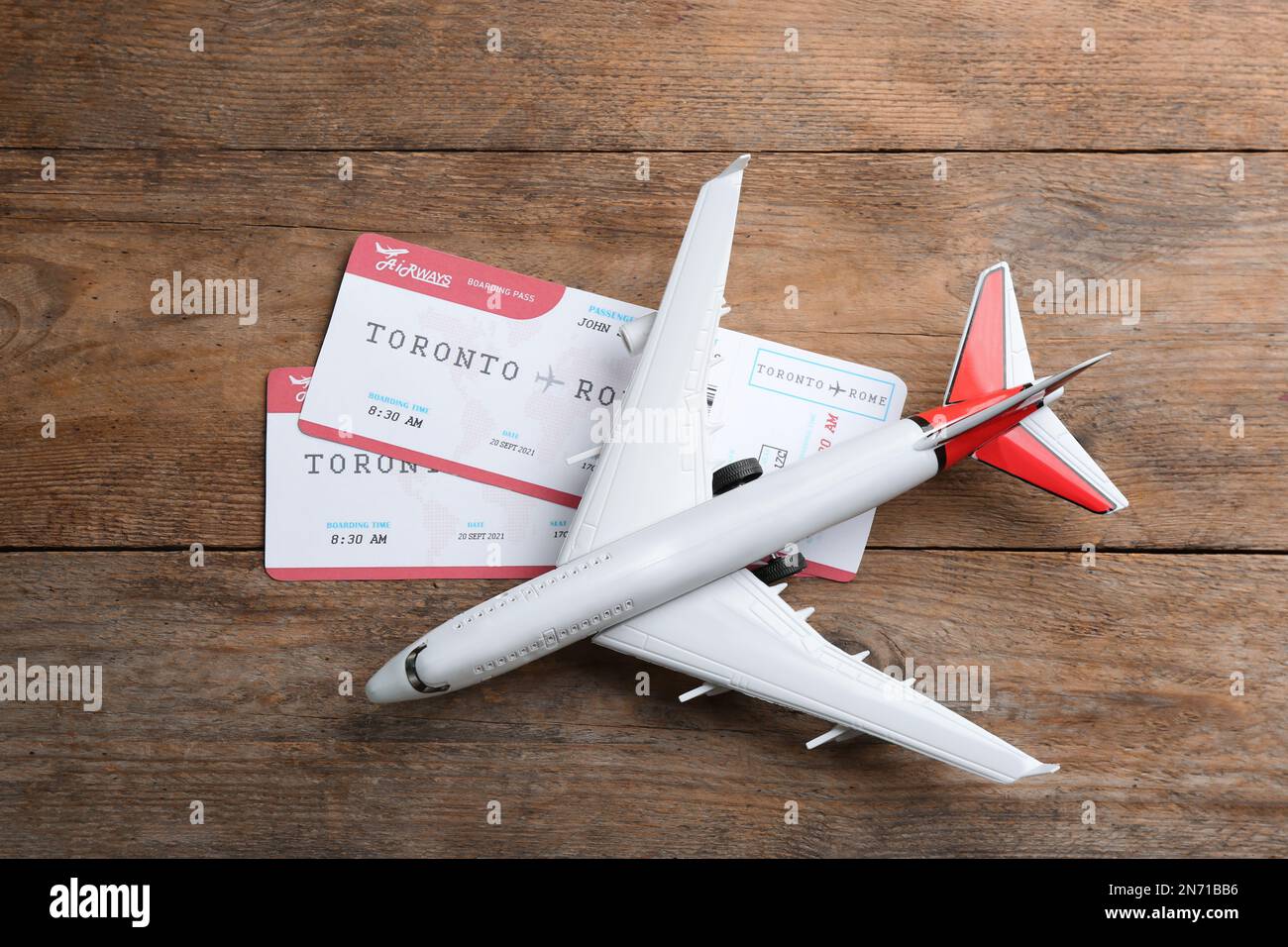Toy airplane with tickets on wooden background, flat lay Stock Photo
