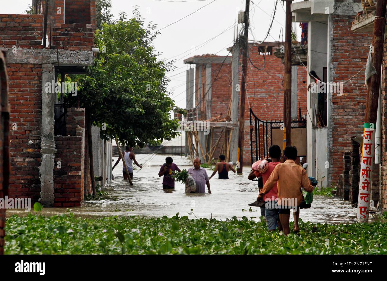 Indian people wade through a street flooded after monsoon rains in ...