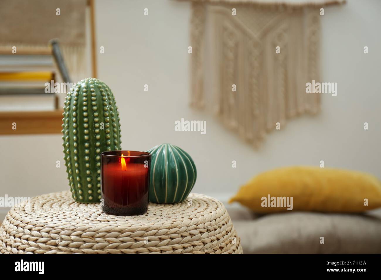 Decorative ceramic cacti and burning candle on wicker stand indoors ...