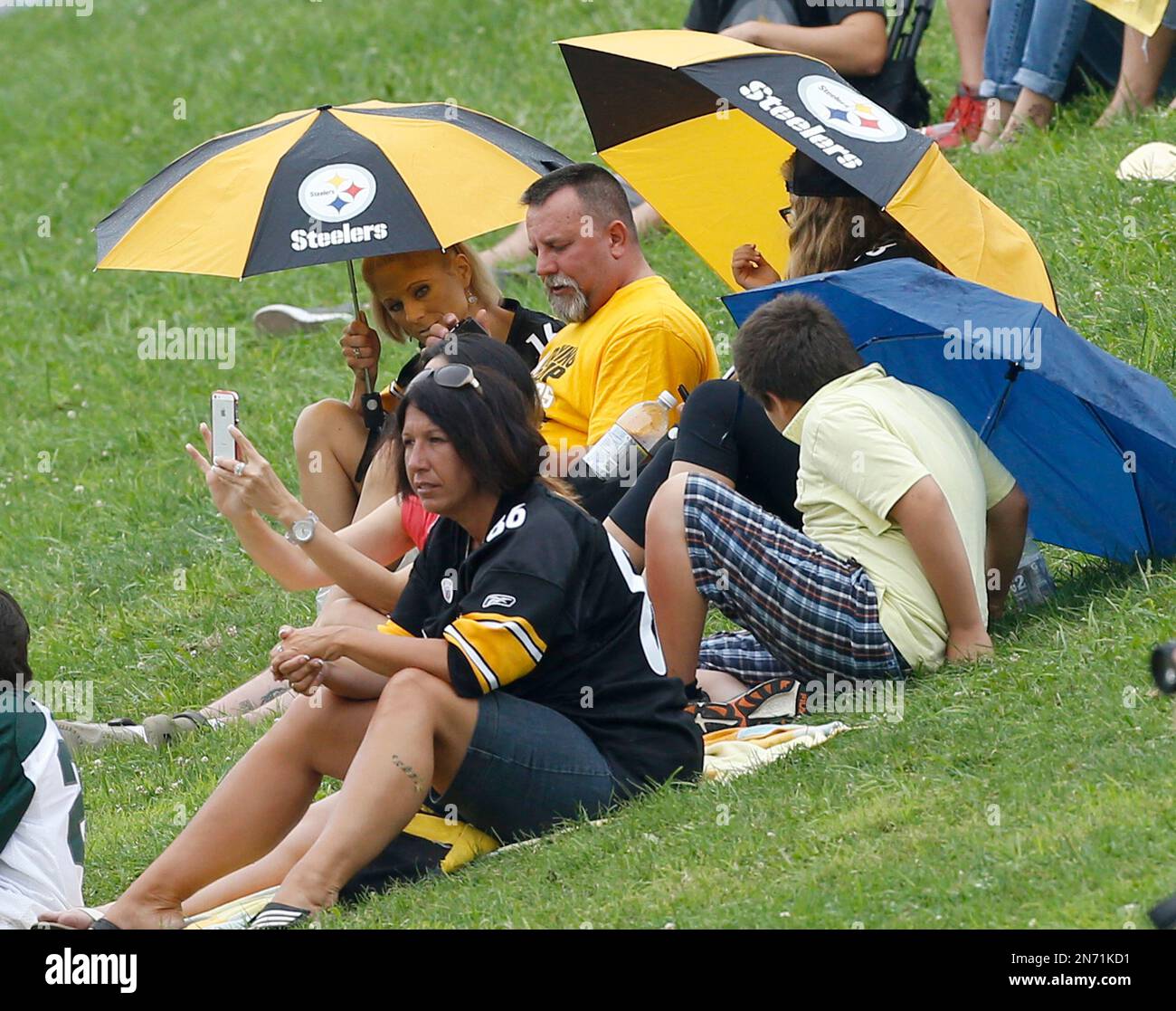 Pittsburgh Steelers fans take shelter under umbrellas as they watch