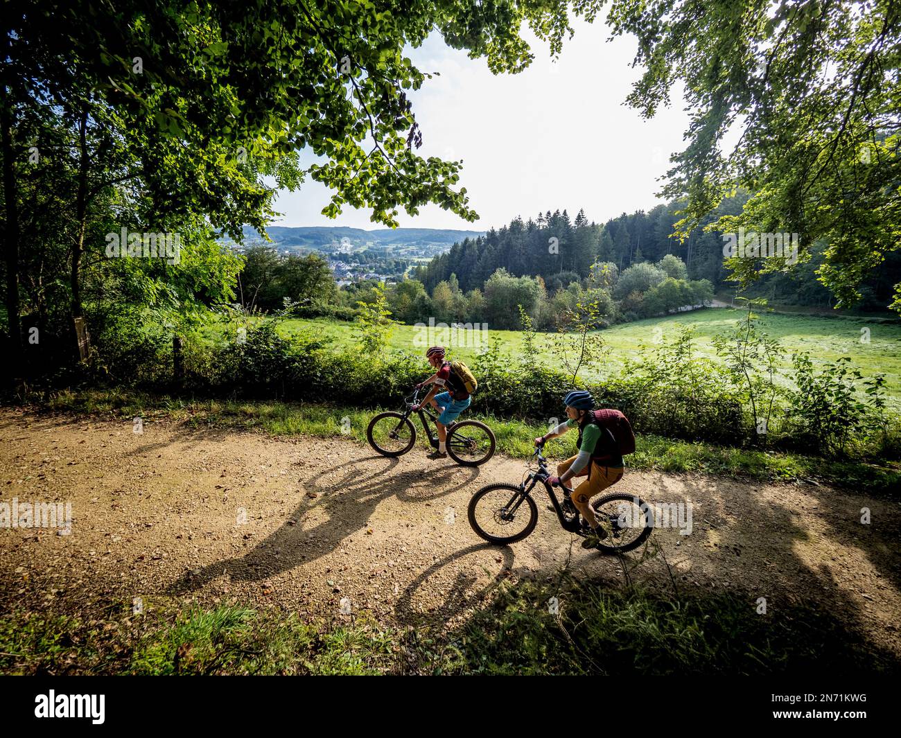 e-mountain biker on forest road in Luxembourg. City of Mersch in the background. Stock Photo