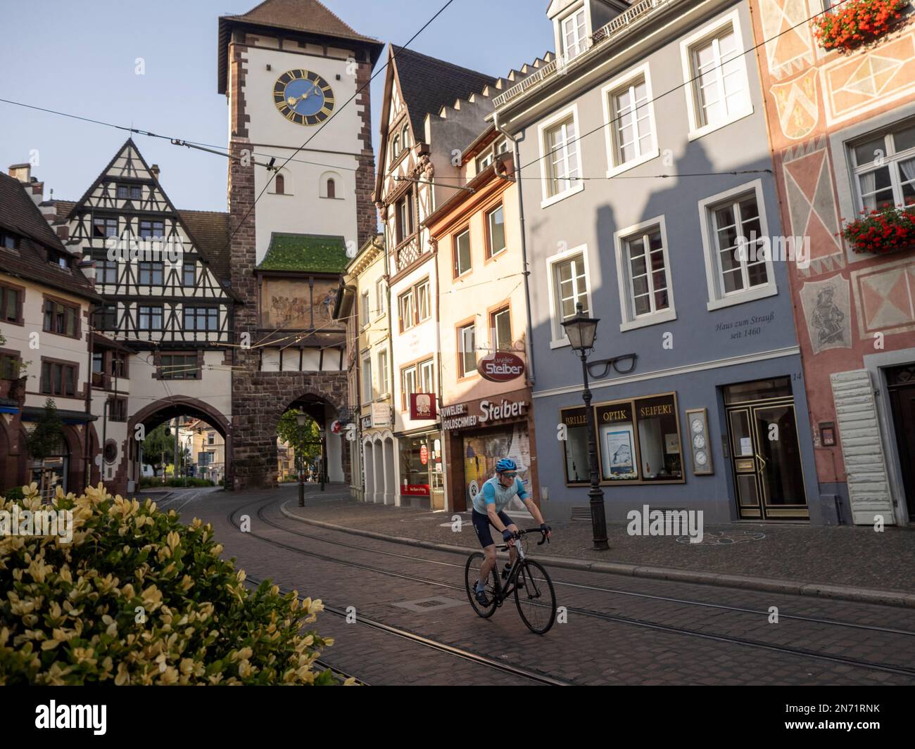 Road cyclist in Freiburg. Passage through the Salzstr in the old town of Freiburg. In the background the Schwabentor. Stock Photo