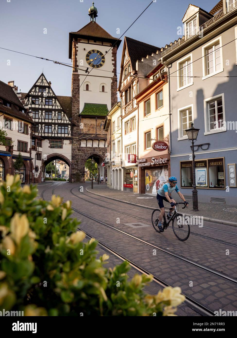 Road cyclist in Freiburg. Passage through the Salzstr in the old town of Freiburg. In the background the Schwabentor. Stock Photo