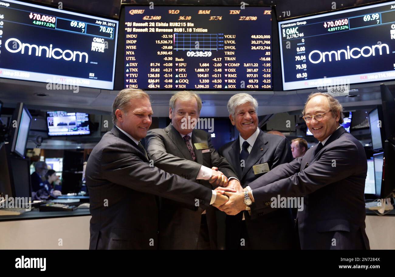 Omnicom Group CFO Randall Weisenburger, left, and President and CEO John Wren, second left, join hands with Publicis Groupe Chairman and CEO Maurice Levy, third left, and CFO Jean-Michel Etienne as they pose for photos on the floor of the New York Stock Exchange Monday, July 29, 2013. Omnicom Group Inc. and Publicis Groupe SA say they are combining in a "merger of equals" that will create the world's largest advertising firm, one worth more than $35 billion. (AP Photo/Richard Drew) Stock Photo