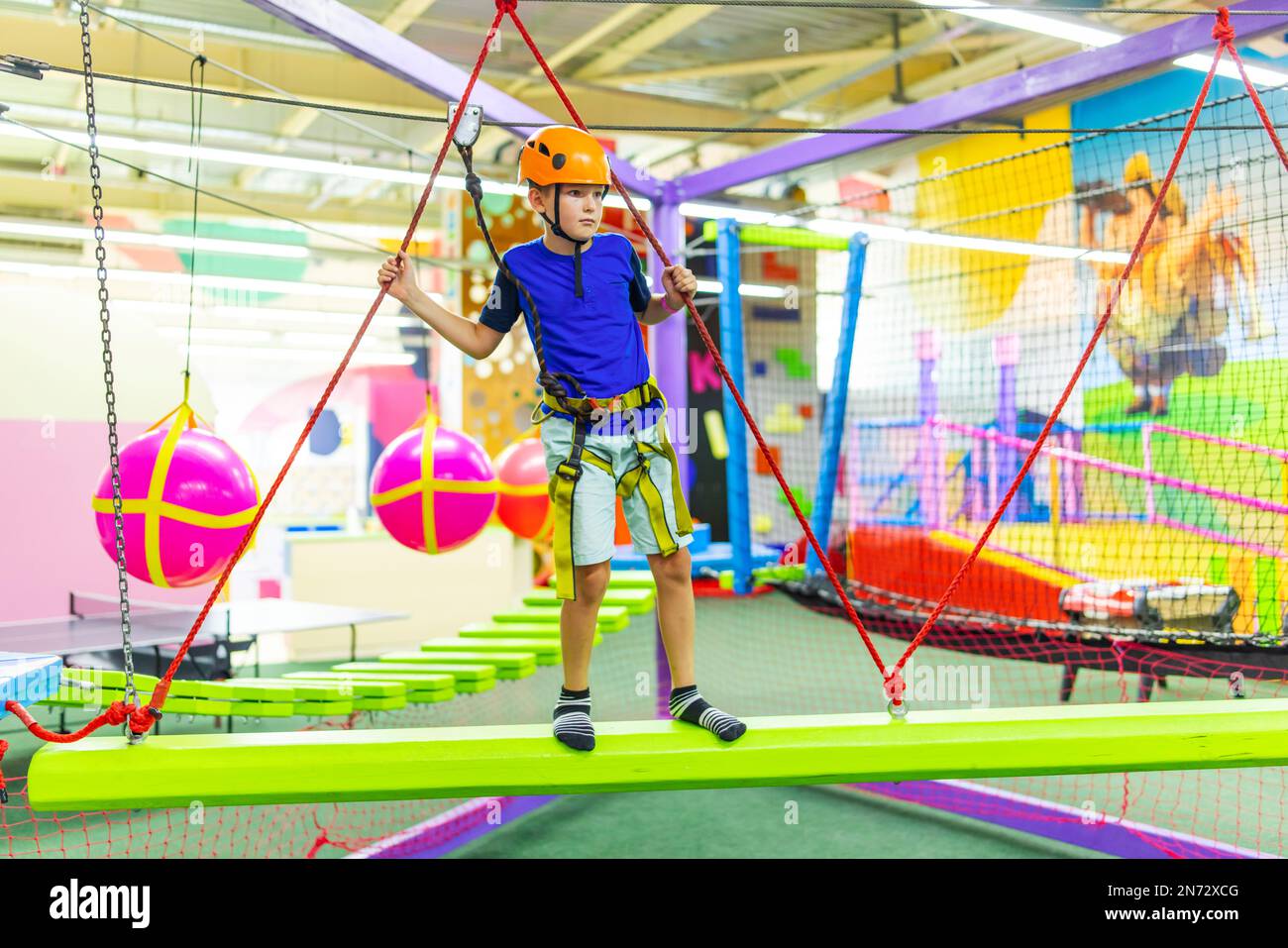 Boy in protective gear holding safety rope and passing obstacle course Stock Photo