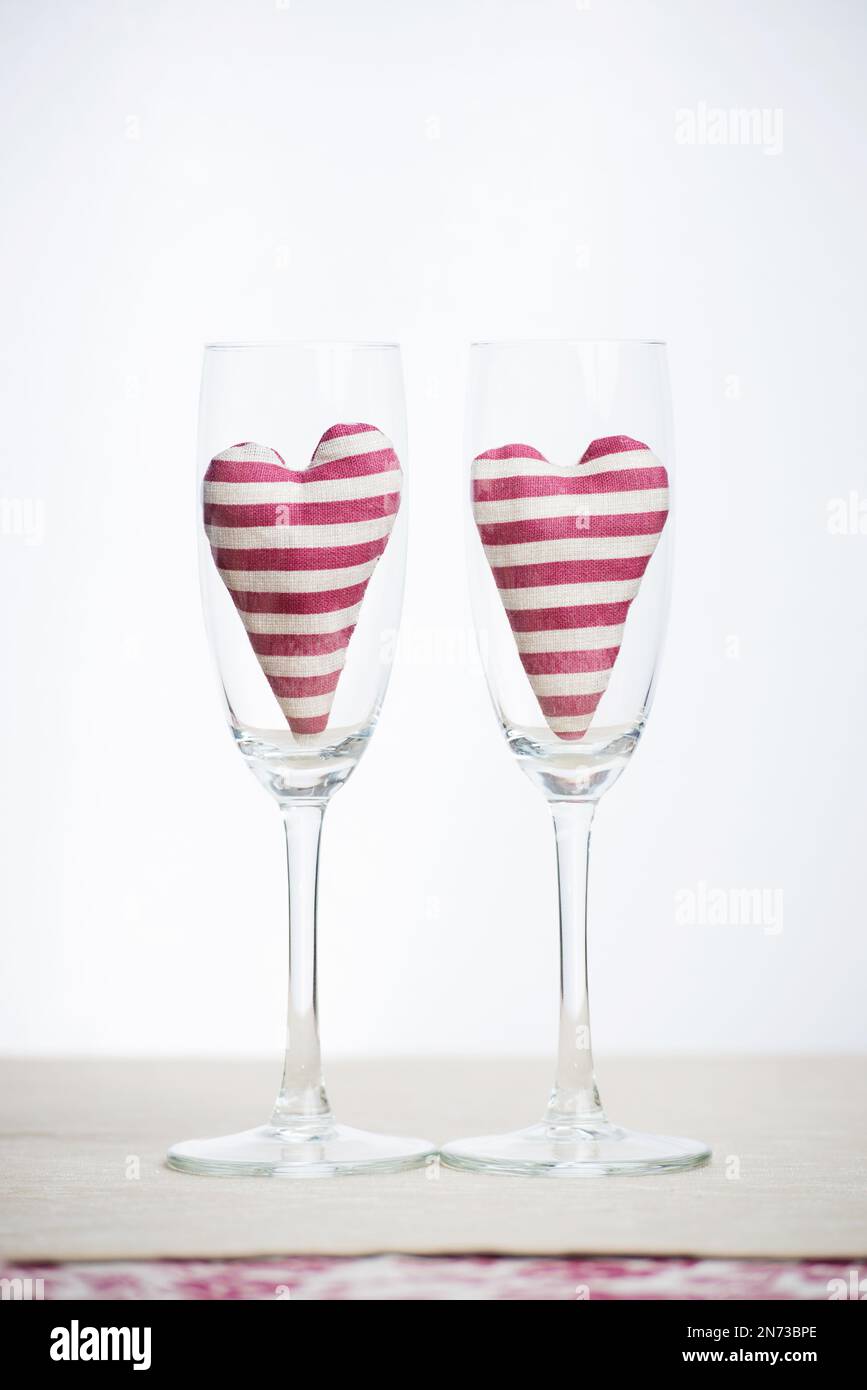 Valentine concept - two stripped hearts in champagne glasses Stock Photo