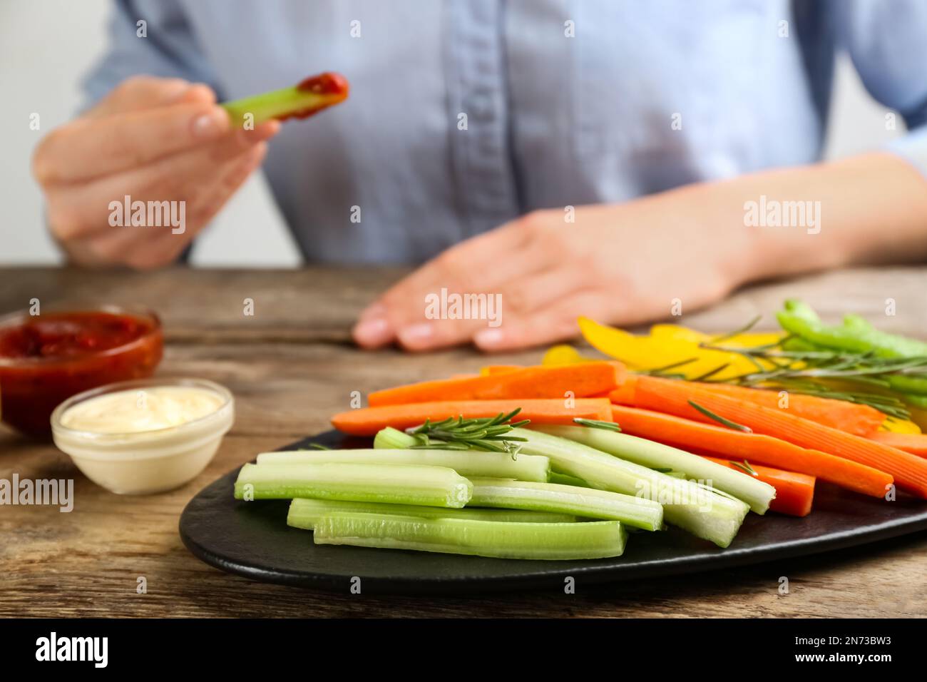 Plate with celery sticks, other vegetables and different dip sauces on