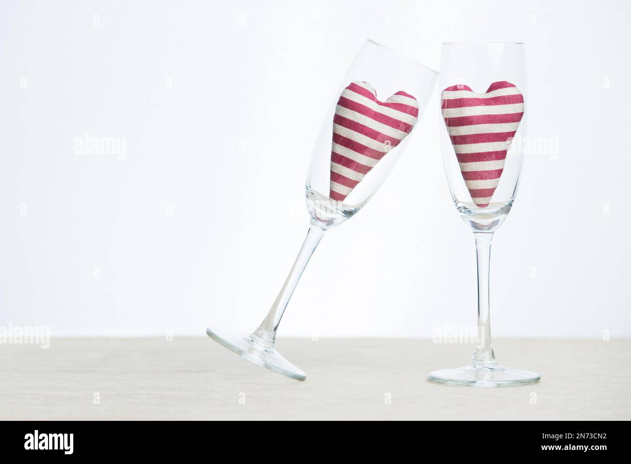 Valentine concept - two stripped hearts in champagne glasses Stock Photo