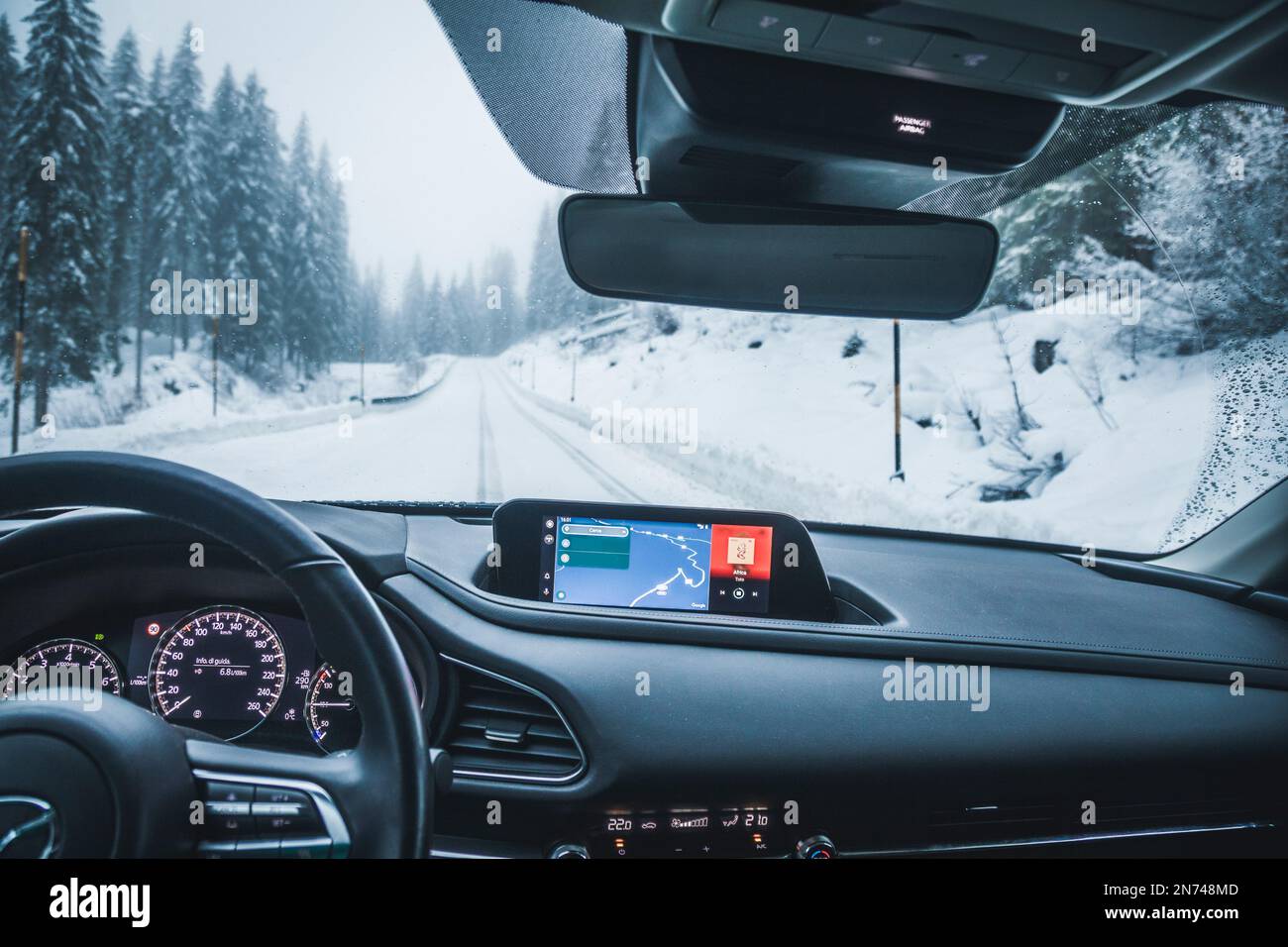 Italy, Veneto, Belluno, a Mazda Motor Corp. CX-30 crossover sport utility vehicle (SUV), inside view, car cockpit, driving on snowy mountain road Stock Photo