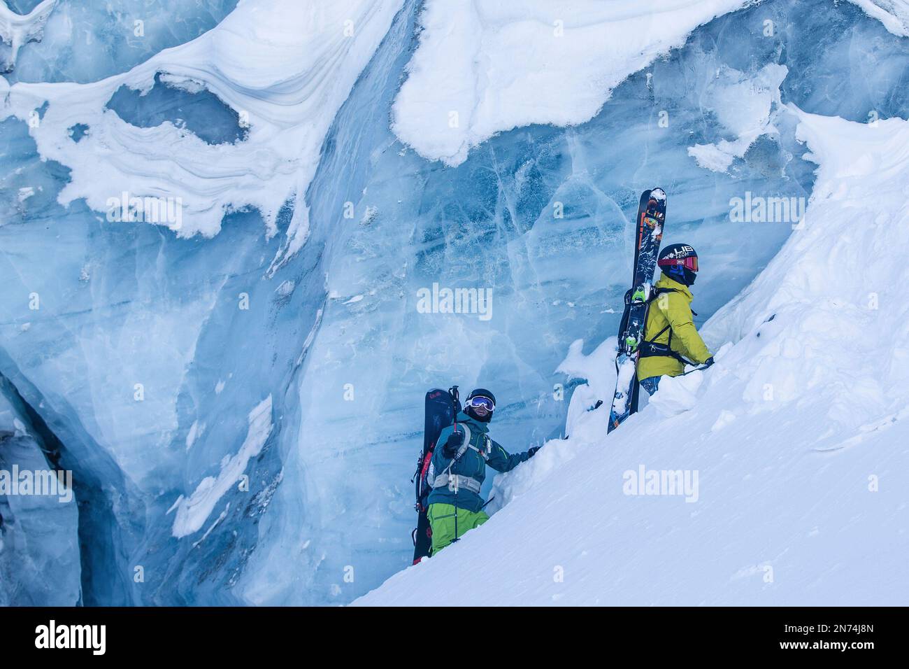 Two professional snowboarders and skiers explore and ski a crevasse / ice cave high up on the Pitztal glacier, Pitztal, Tyrol, Austria Stock Photo