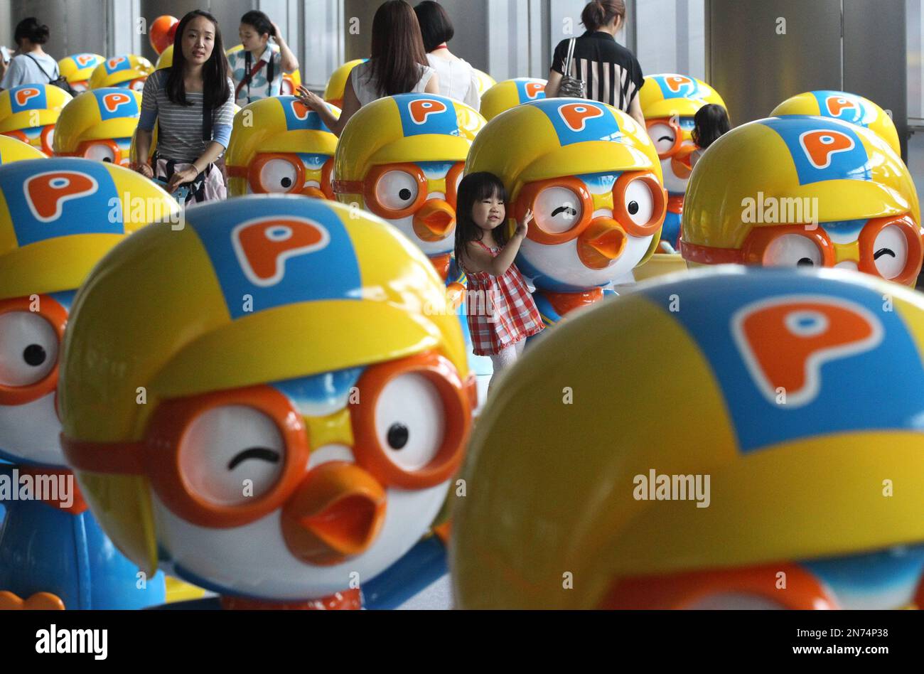 A girl poses with a doll featuring South Korean animation character ...