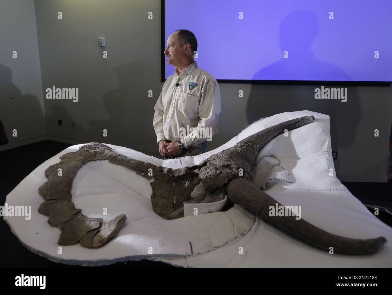 Paleontologist Alan Titus stands next to a fossil of a 