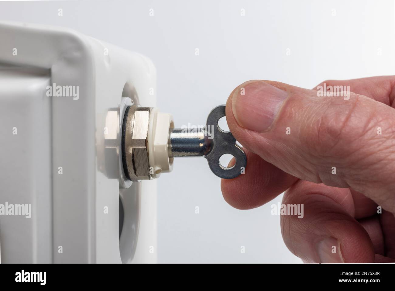 Man hand with bleeder key, bleeder valve, radiator, symbol image, bleed