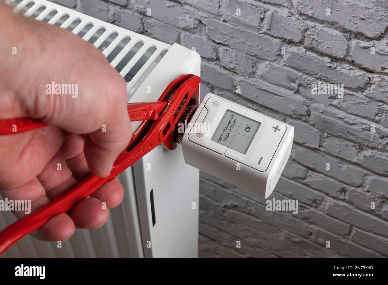Man's hand with water pump pliers mounted WLAN radiator thermostat