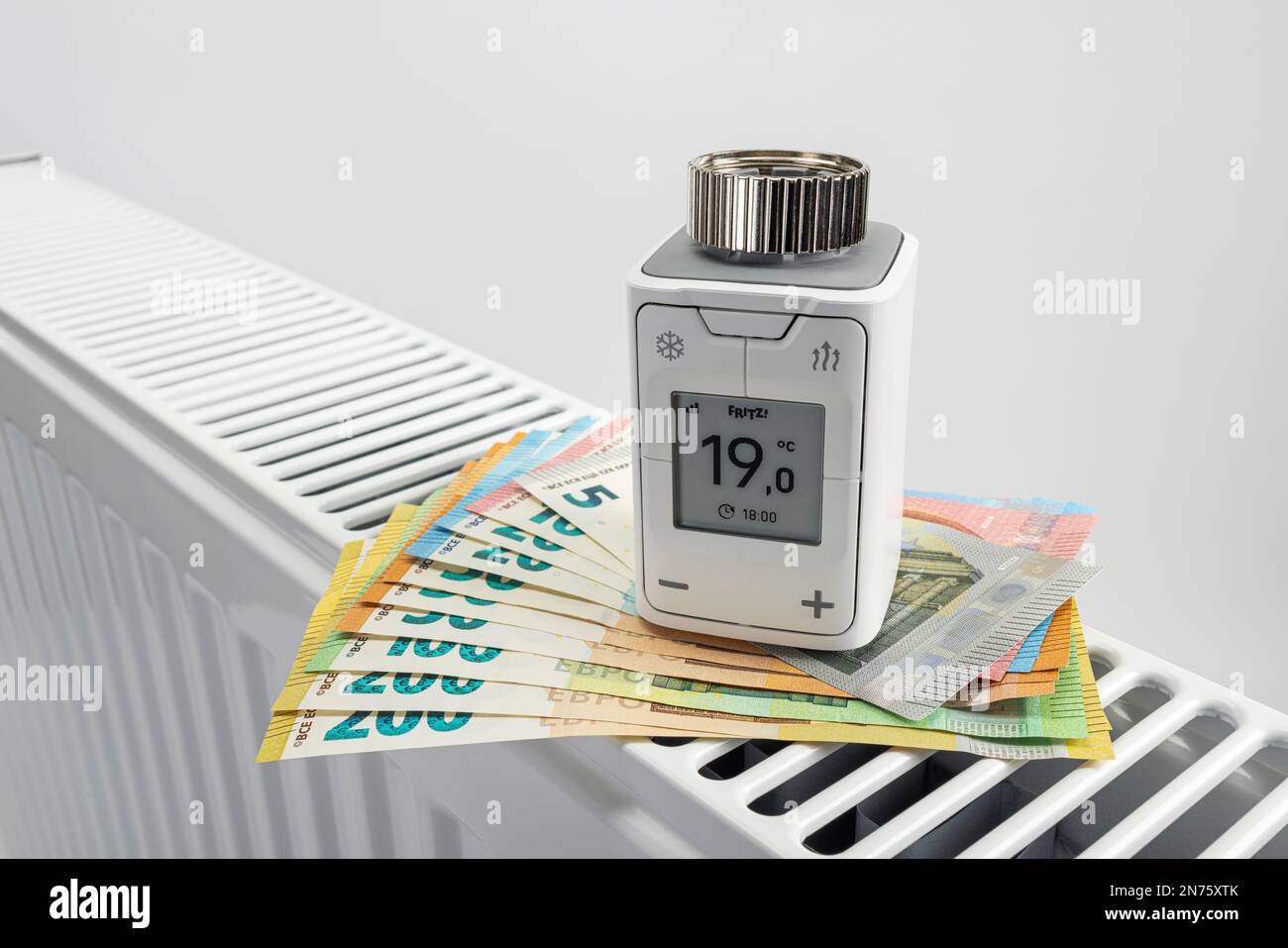 WLAN radiator thermostat FRITZ! DECT 302, euro bills on radiator, white background, icon image, replace heating thermostat, save energy costs, Stock Photo