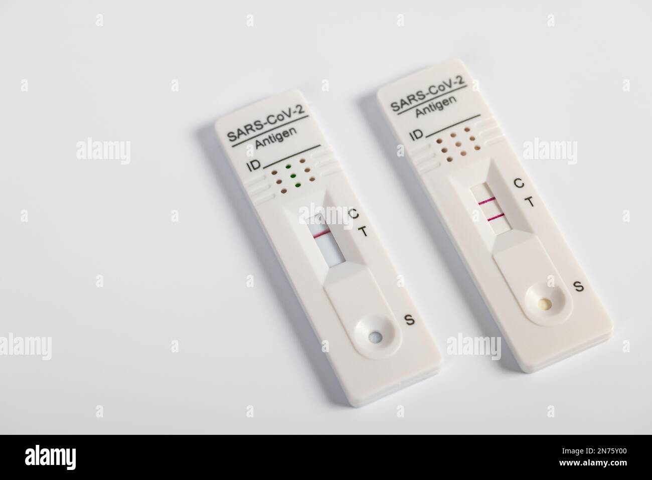 Two Rapid SARS-CoV-2 antigen test cassettes with negative and one positive test result, white background, Stock Photo